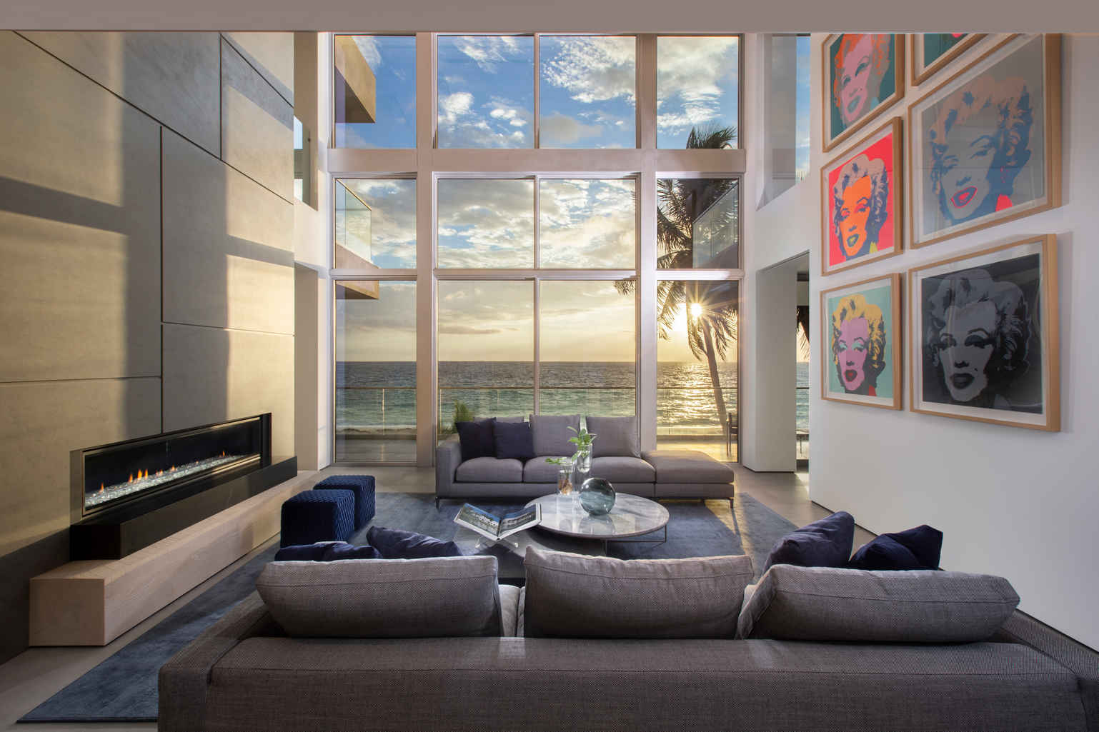 A contemporary oceanfront retreat home featuring a living room with a built-in fireplace, pop-art decor, and an ocean view.