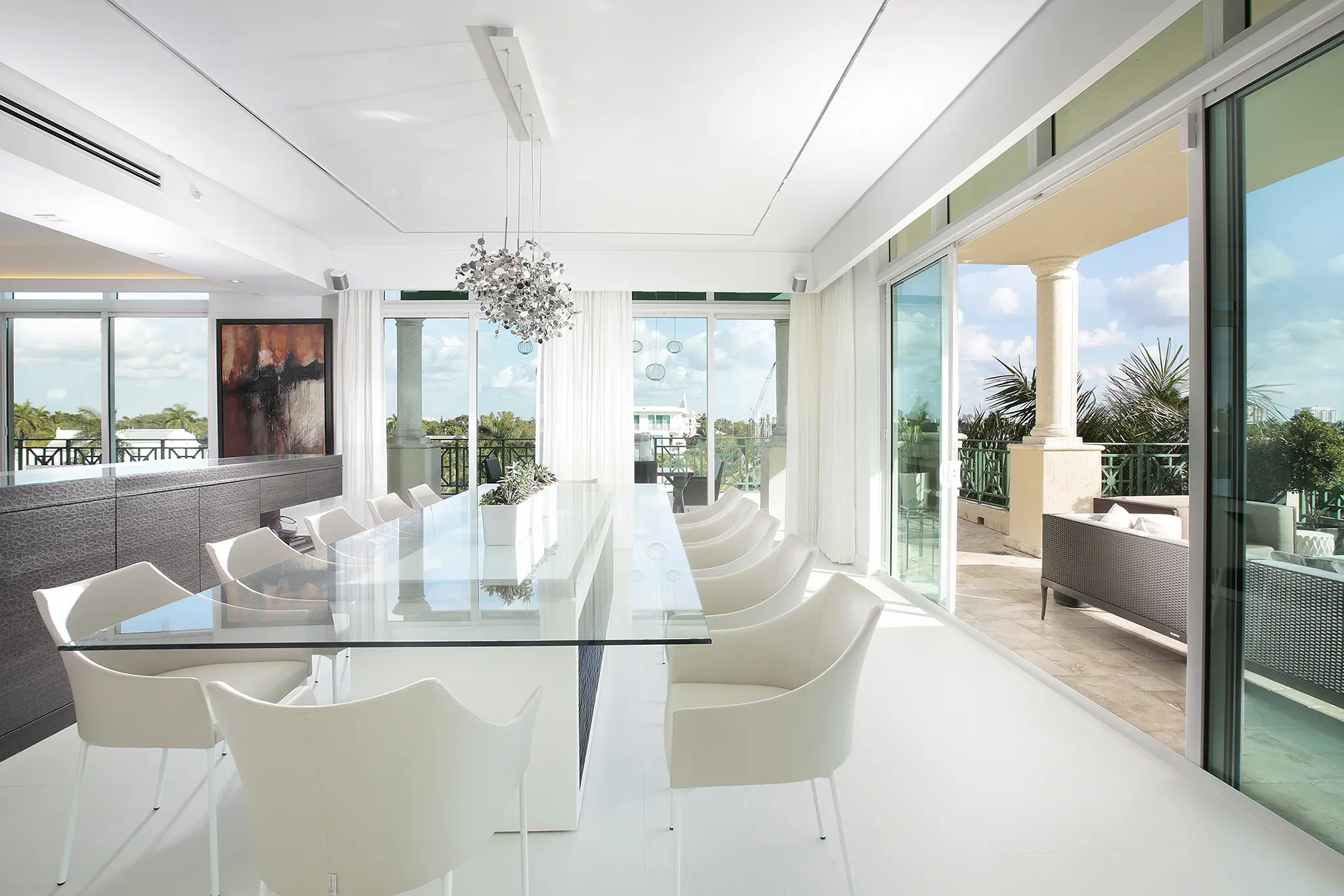 White dining room design with glass table and floor to ceiling windows