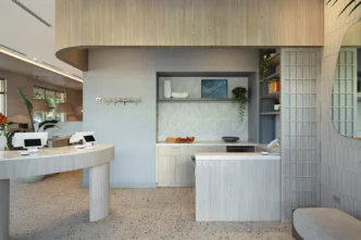 Fort Lauderdale restaurant pickup area with curved light wood counters, open shelving, terrazzo flooring, and branded signage