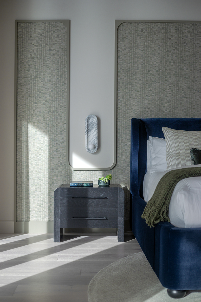 Textured wallpaper framed within vertical architectural moldings in a luxury bedroom design.
