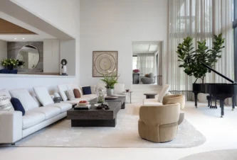 Serene living room with a grand piano, neutral tones, and warm wood finishes in a Coral Gables luxury home renovation.