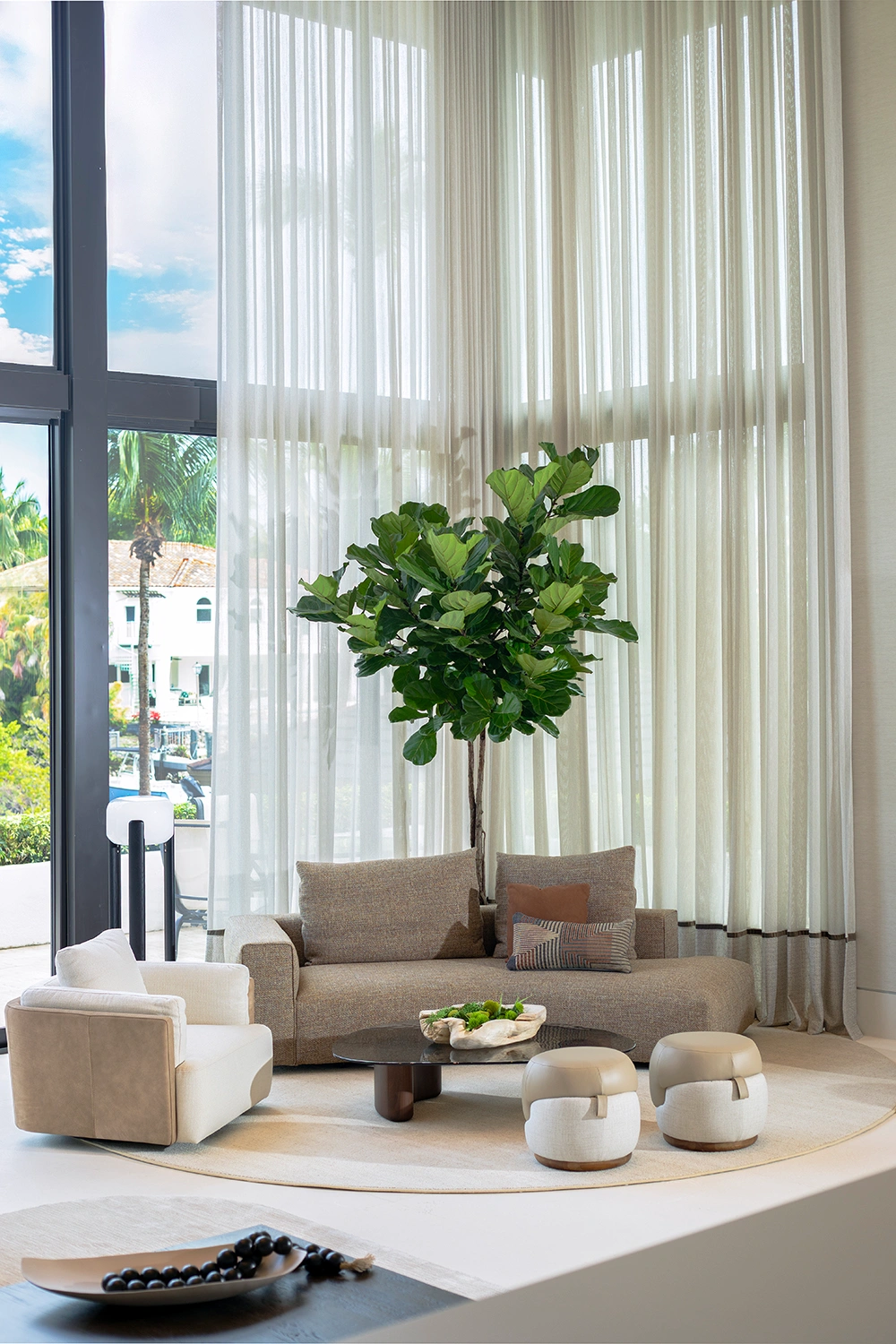 Airy seating area with double-height sheer curtains and neutral furniture in a Coral Gables luxury home renovation.