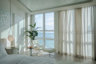 A living room showcasing modern coastal interior design with natural light and oceanfront views in Bal Harbour.