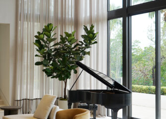 Airy seating area with double-height sheer curtains and neutral furniture in a Coral Gables luxury home renovation.