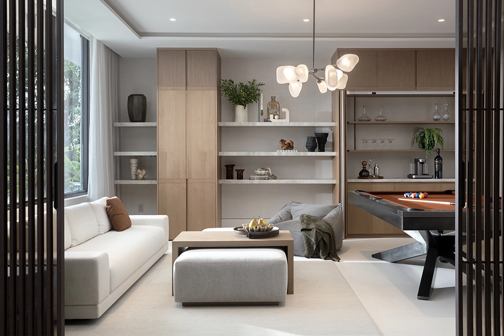 Modern family room interior design featuring a pool table, white sofa, and custom built-in shelving.
