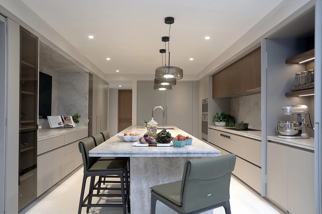 Open concept modern kitchen design with a large marble island, bar seating, and sleek beige cabinetry.