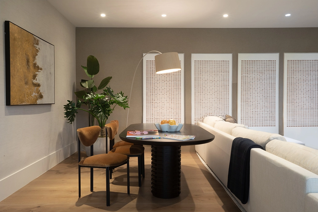 Multifunctional family room interior design with a dark dining table, camel chairs, and a deep white sofa.
