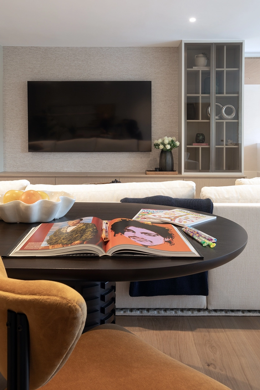 Cozy sitting area with round wooden table and TV wall in a modern Coral Gables residence.