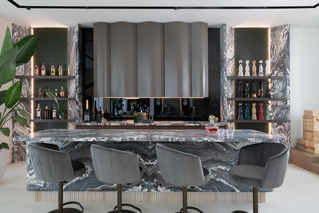 Custom bar with curved dark marble counter and sculptural metal cabinetry in Miami Beach