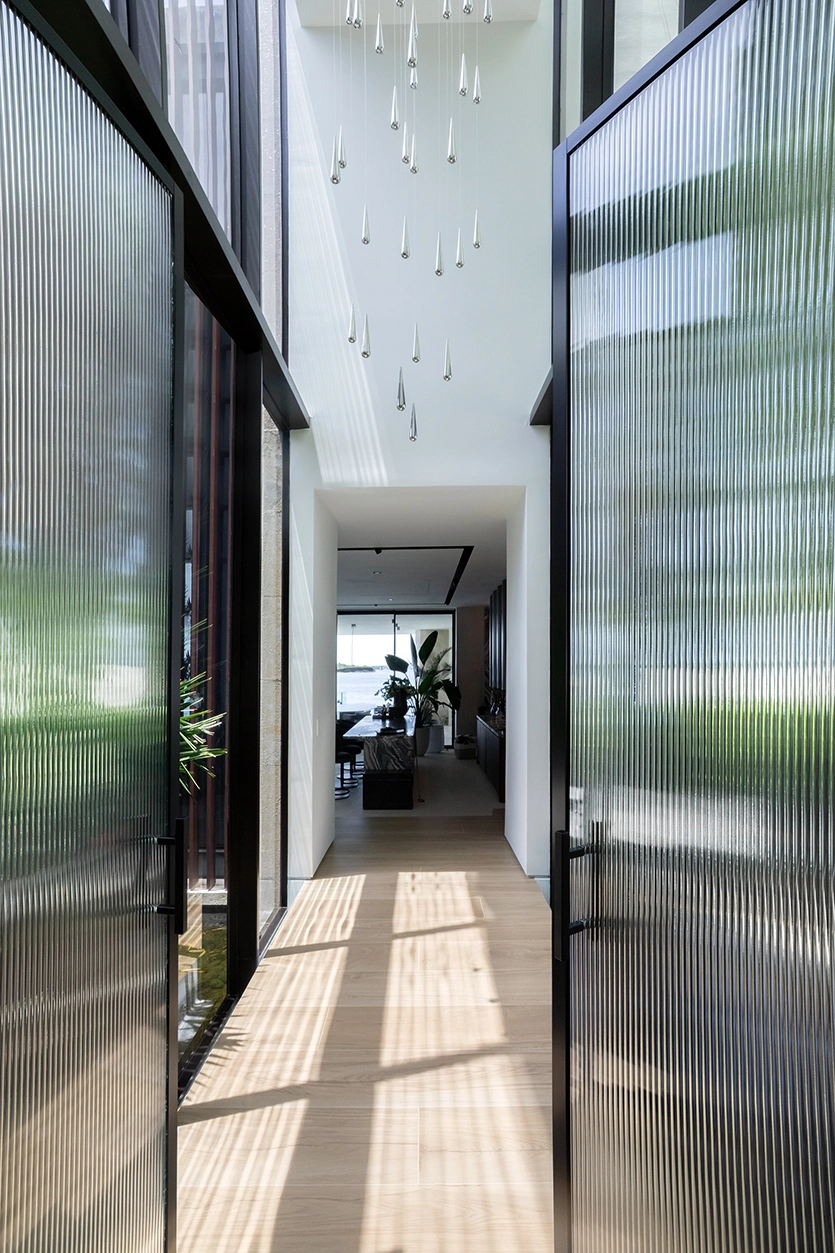 Fluted glass doors and hallway entry leading to social spaces in a luxury Miami Beach residence